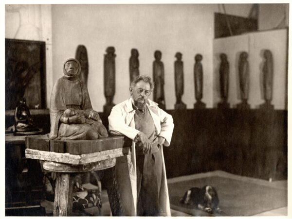 Auf der Schwarzweiß-Fotografie ist der Künstler Ernst Barlach in seinem Atelier zu sehen, im Jahr 1935. Neben ihm ist eine Holzskulptur, sie trägt den Titel "Mutter und Kind".